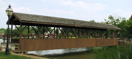 A covered bridge stretching over a pond.