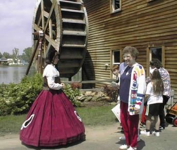 A woman in old style garb leading a tour group.